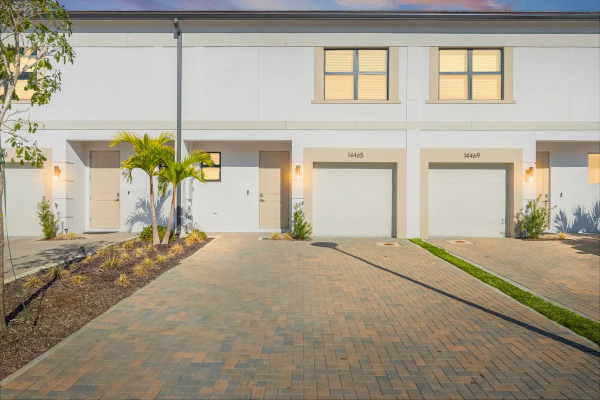 Amber townhomes at dusk with lit windows and a paver drive